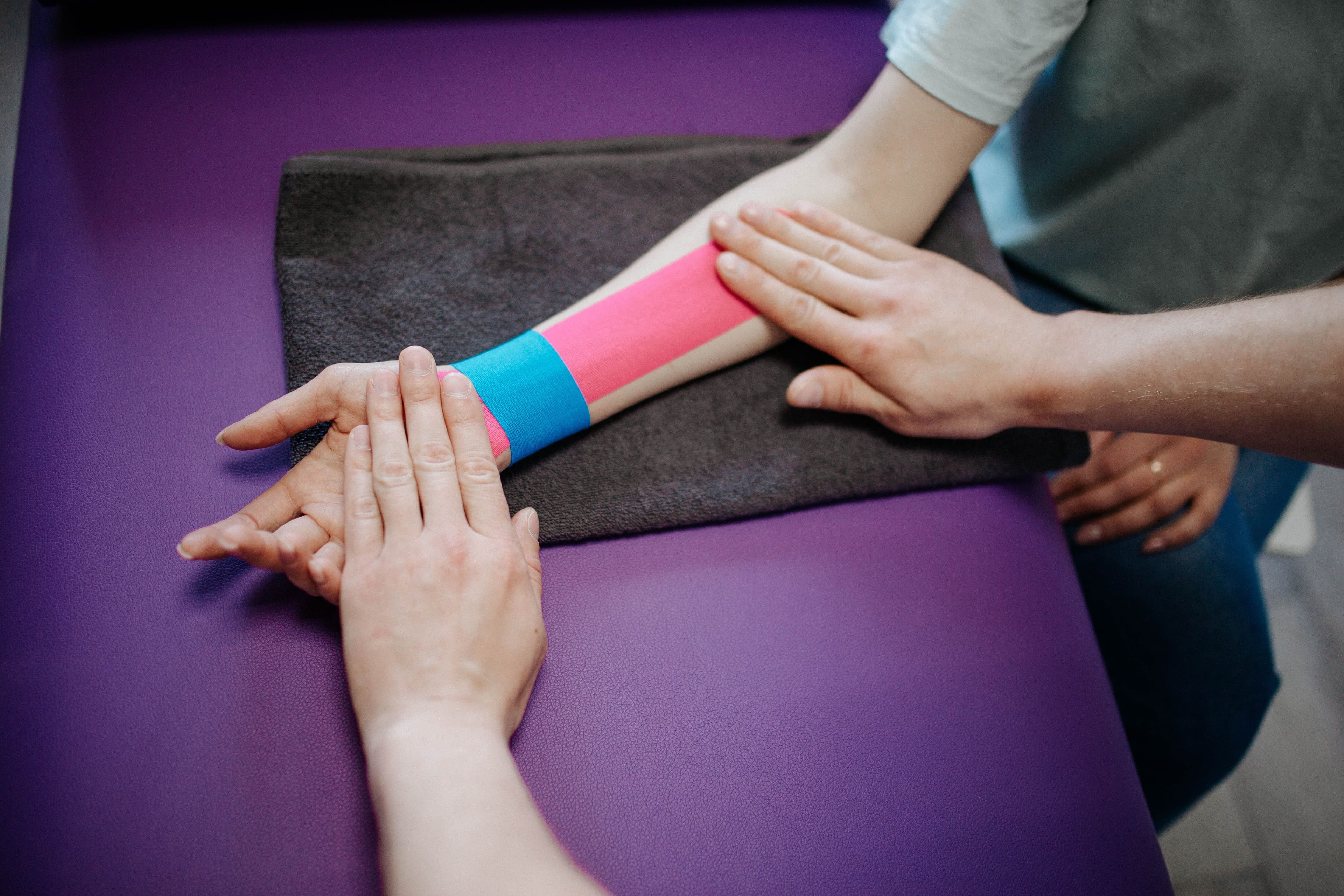 Therapist applying kinesiology tape to an athlete's forearm